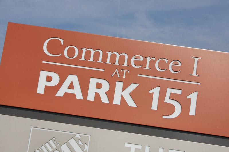 Sign with orange background reads "Commerce I at Park 151" against a blue sky.