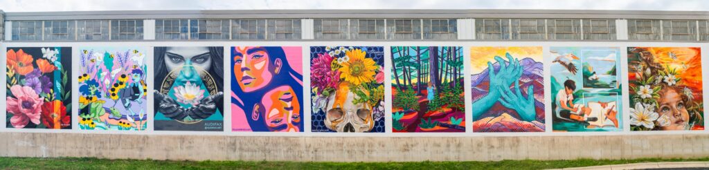 A series of seven large, colorful murals painted on an exterior wall featuring flowers, portraits, landscapes, and surreal imagery.
